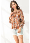 Woman wearing a brown polka dot blouse and denim shorts on a white background