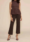 A woman modeling a sleeveless peplum top and matching cropped wide-leg pants in a brown and black houndstooth pattern, paired with dark brown heeled sandals, against a solid beige studio background.