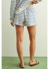 Person wearing striped shorts and a long-sleeve shirt on a plain background
