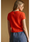 Woman wearing a red knitted top against a beige background