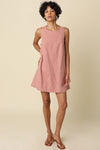 Woman wearing a pink striped dress against a beige background