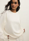 Woman wearing a white sweater against a plain background