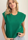 Woman wearing a green sleeveless top against a plain background