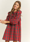 Woman wearing a red plaid dress against a plain background