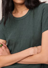 Person wearing a green t-shirt with arms crossed against a neutral background