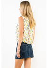 Woman wearing a sleeveless floral top and denim skirt on a white background