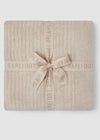 Beige textured blanket with a bow and 'Barefoot Dreams' branding on a white background