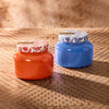 Two decorative jars, one orange and one blue, on a textured surface with a neutral background.