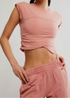 Person wearing a pink crop top and pants against a plain background