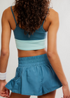 Person wearing a blue sports bra and skirt set on a plain background