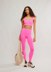 Woman wearing a pink sports bra and leggings set on a white background