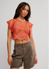 Woman wearing a lace top and cargo shorts on a plain background