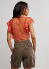 Woman wearing a lace top and shorts on a plain background