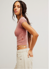 Woman wearing a pink crop top and beige pants against a plain background