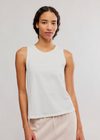 Person wearing a white sleeveless top and light-colored pants on a plain background