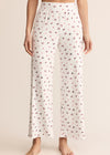 White pajama pants with a subtle pattern worn by a person on a beige background
