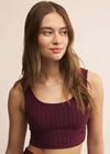 Woman wearing a maroon ribbed crop top against a beige background