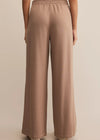 Brown wide-leg pants worn by a person on a beige background