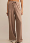 Brown wide-leg pants worn by a person on a beige background