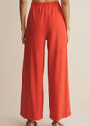 Red wide-leg pants worn by a person on a beige background