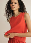 Woman wearing a red sleeveless top against a beige background
