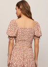 Woman wearing a floral dress with puff sleeves on a plain background