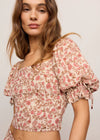 Woman wearing a floral top with puffed sleeves on a plain background
