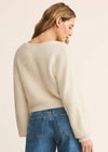 Woman wearing a cream sweater and blue jeans on a beige background