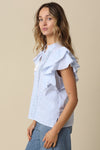 Woman wearing a light blue and white striped blouse with ruffled sleeves on a beige background