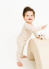 Child wearing a white onesie on a white background