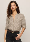 Woman wearing a checkered shirt and black pants against a plain background