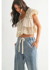 Woman wearing a lace top and wide-leg pants on a white background