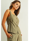 Woman wearing a green sleeveless blazer over a matching dress against a plain background