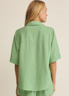Person wearing a green shirt and shorts set on a beige background