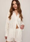Woman wearing a white lace outfit on a plain background