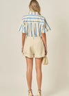 Woman wearing a striped shirt and beige shorts against a plain background