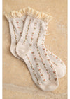 Pair of white socks with floral embroidery on a textured beige background