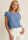 Woman wearing a blue top and white shorts against a beige background