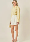 Woman wearing a yellow shirt and white skirt with a beige background