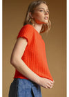 Woman wearing an orange knitted top against a brown background