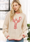 Woman wearing a cream sweater with red lobster design indoors