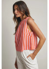Woman wearing a sleeveless striped top and white pants against a plain background