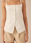 White sleeveless blazer over beige shorts on a neutral background