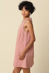 Woman wearing a pink striped dress against a beige background