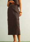 Person wearing a brown skirt with cargo pockets on a plain background