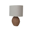 A table lamp with a textured light gray fabric drum shade and a round, woven natural brown rattan base, shown against a plain white background.