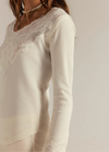 White long-sleeve top with lace detailing on a plain background