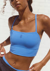 Woman wearing a blue sports bra and black shorts against a light background