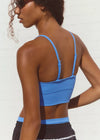 Woman wearing a blue sports bra and black shorts against a white background