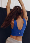 Person wearing a blue sports bra and gray leggings with a white background